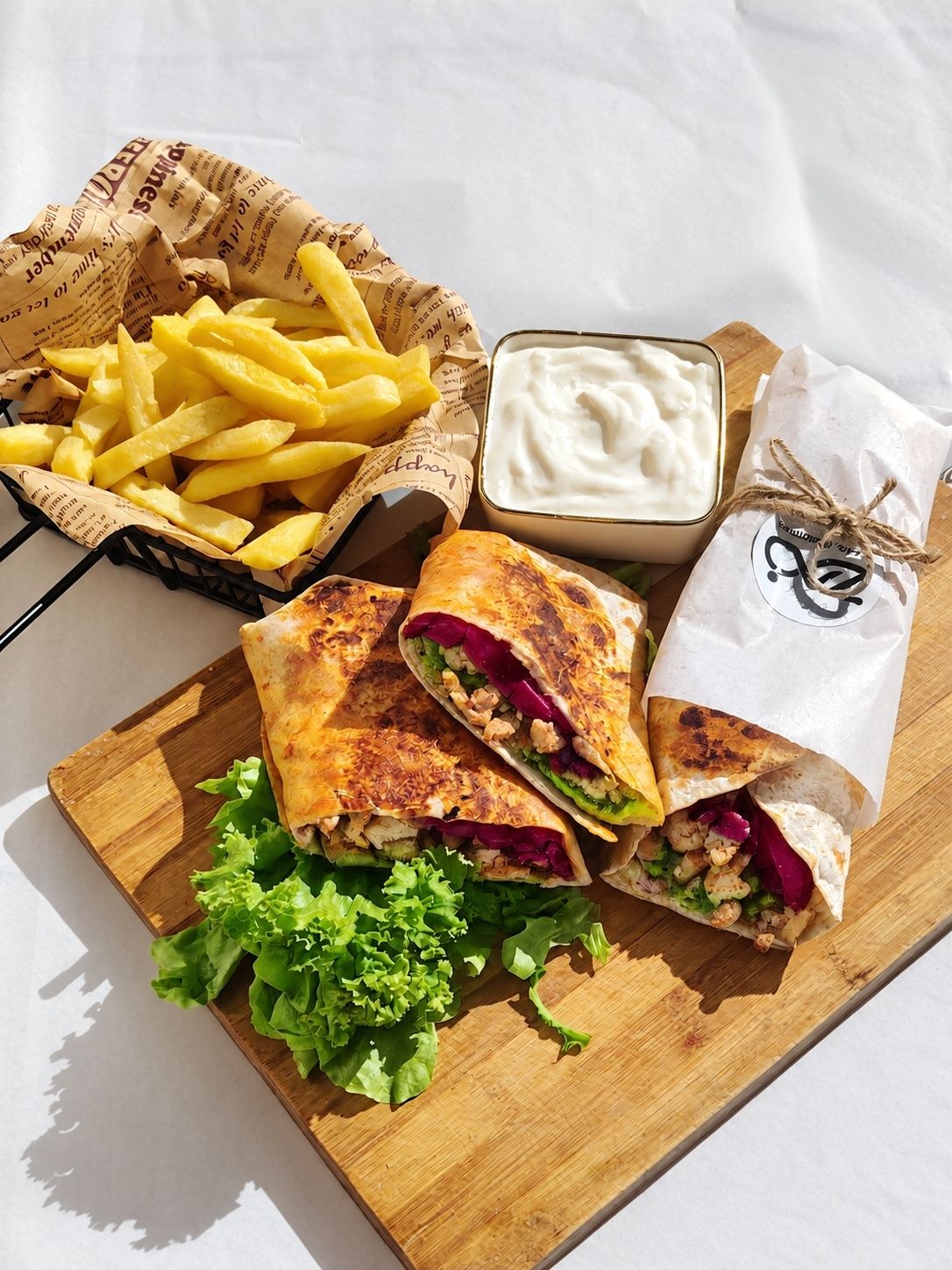 Chicken wraps with chips, lettuce and white sauce on a board