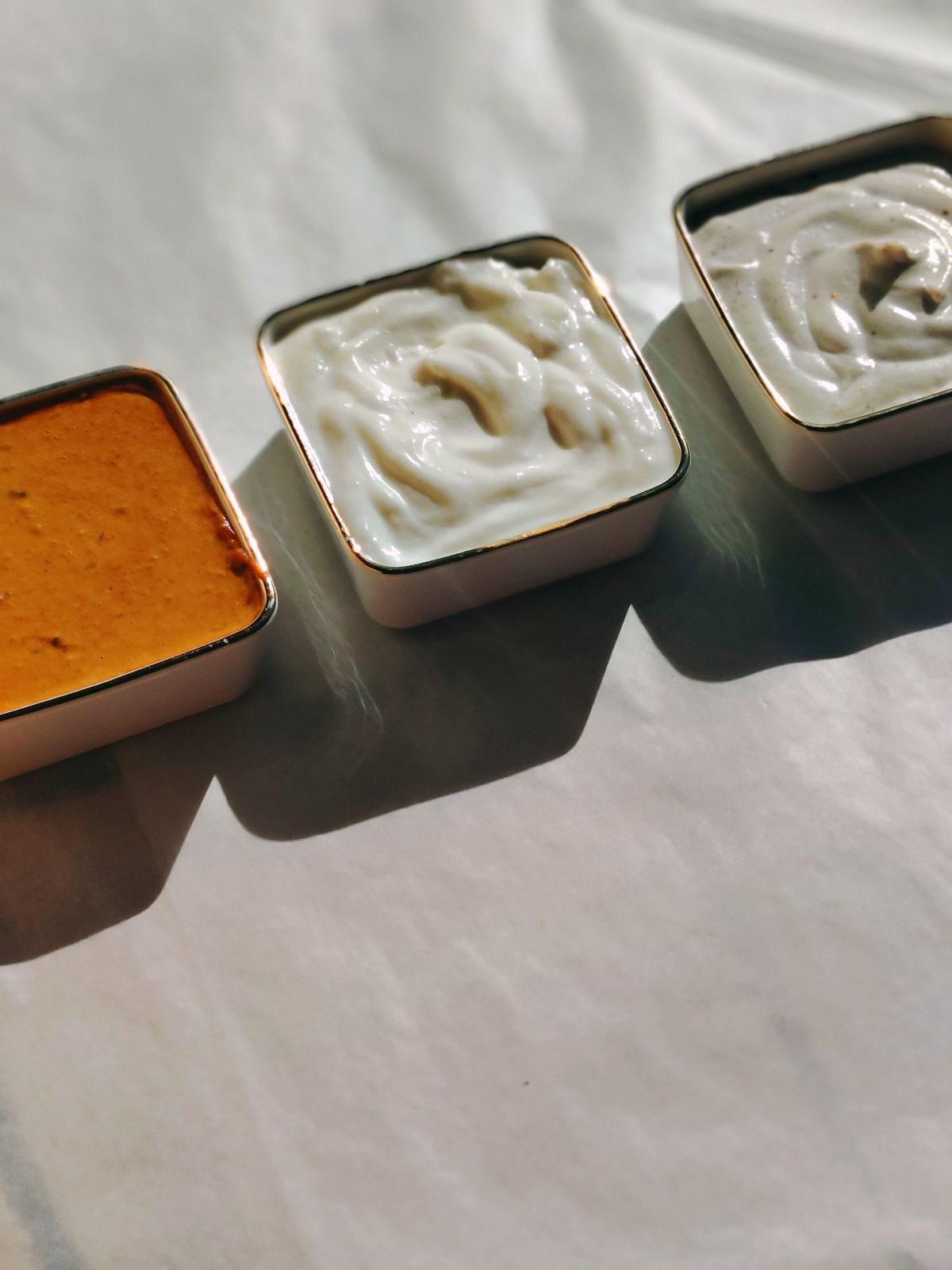 Three house sauces in gold-rimmed bowls